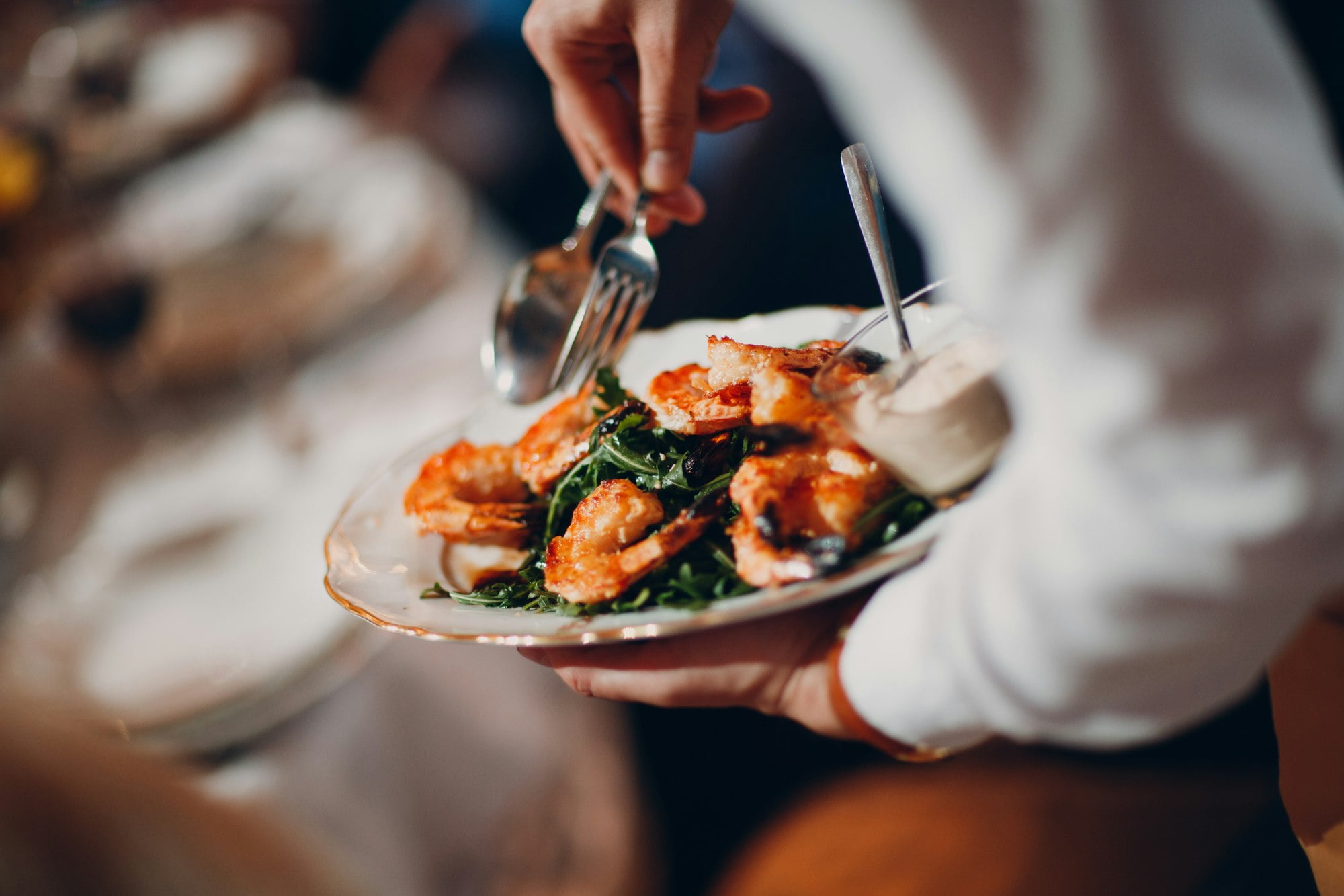 Waiter serves shrimp with arugula.